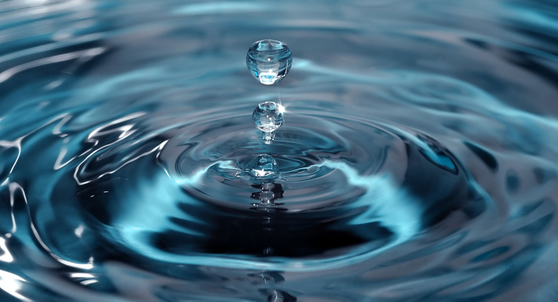 A close-up of water dripping and creating ripples in a pool of water